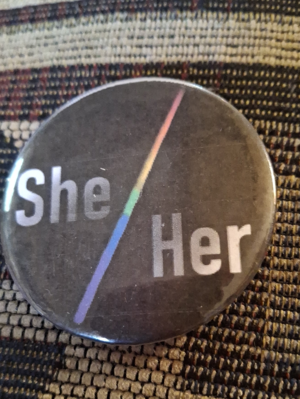 She/Her Pronoun Pin – Black with Rainbow Stripe
